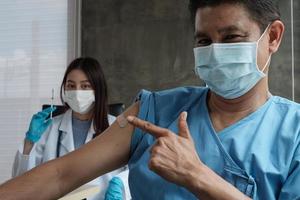 ritratto, maschera facciale asiatica maschio paziente sorridente, vaccinando contro il coronavirus covid-19 con un medico in ospedale, il braccio con cerotto medicinale. le iniezioni sono cure mediche.