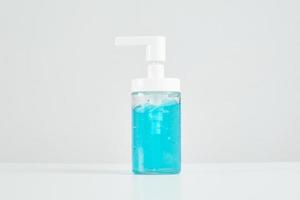 primo piano, alcool blu in una bottiglia di plastica trasparente su sfondo bianco usato per pulire le mani per prevenire la diffusione di malattie e infezioni da batteri coronavirus covid-19 e per una buona igiene sanitaria. foto