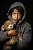 lutto immigrante ragazzo stringendo logoro orsacchiotto orso isolato su un' grigio pendenza sfondo foto