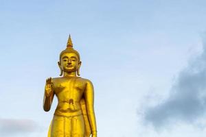 Una statua dorata del Buddha con il cielo sulla cima della montagna al parco pubblico del comune di Hat Yai, provincia di Songkhla, Thailandia foto