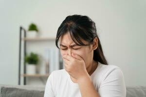 giovane donna avuto un' naso allergia starnuti seduta su il divano a casa. influenza, influenza, malato, febbre, malattia. assistenza sanitaria e medico concetto. foto