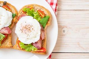 pane integrale tostato con verdure, pancetta e uovo o uovo alla benedict, per colazione foto