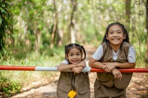 asiatico poco ragazze Esplorare natura attraverso ingrandimento bicchieri e binocolo nel il parco. formazione scolastica, campo viaggi, ricerca, e scoperta concetti. foto