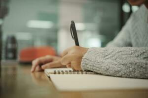 alunno preparazione per Università test, esame, lettura prenotare, studiando manuale, scrittura Appunti, fabbricazione sommario per classe rapporto. apprendimento posto di lavoro tavolo, mani con matita vicino su foto