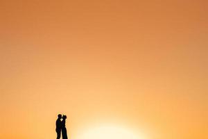sagome di una giovane coppia felice su uno sfondo di arancio tramonto nel deserto di sabbia foto