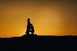 sagome di una giovane famiglia felice felice contro un tramonto arancione foto