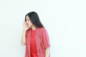 ritratto di bellissimo asiatico donna indossare rosso attrezzatura con sussurrando gesto foto