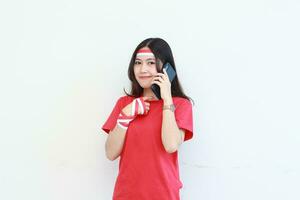 ritratto di bellissimo asiatico donna indossare rosso attrezzatura festeggiare Indonesia indipendenza giorno mentre chiamata con sorridente espressione foto
