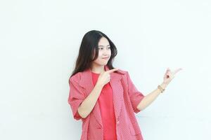 ritratto di bellissimo asiatico donna indossare rosso attrezzatura puntamento per il lato per copia spazio con sorridente gesto foto