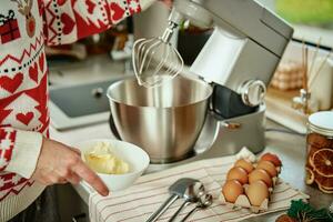 donna cucinando a casa cucina, uso elettrico miscelatore per preparazione Impasto foto