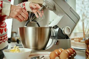 donna cucinando a casa cucina, uso elettrico miscelatore per preparazione Impasto foto