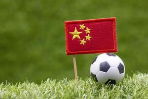 il pallone da calcio e la bandiera della Cina sono sullo sfondo dell'erba verde foto