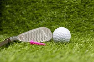 la pallina da golf con il tee e il ferro sono sull'erba verde foto