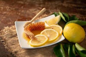 succo di limone con miele su tavola di legno, limoni e foglie di salvia foto