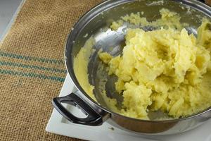 schiacciare le patate lesse con uno schiacciapatate fatto in casa foto