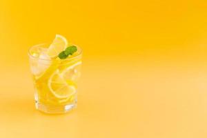acqua detox al limone in un bicchiere su fondo arancio foto