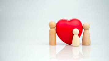 il concetto di Salute assicurazione e medico benessere. un' di legno Bambola con un' rosso cuore su un' bianca sfondo rappresenta protezione, ricevente benefici. Salute assicurazione e accesso per trattamento. foto