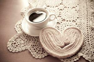 bianca tazza di nero caffè e un' dolce burroso biscotto su il tavolo foto