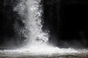 spruzzi acqua a partire dal potente cascata con buio sfondo. foto