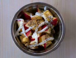 un' fatti in casa insalata di Mela e ananas pezzi sormontato con chai semi e dolce Maionese servito nel un' inossidabile acciaio ciotola fa per un' salutare prima colazione. foto