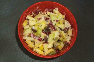 tritato mela, melone, ananas sormontato con chia semi e Maionese servito nel un' rosso ciotola. foto