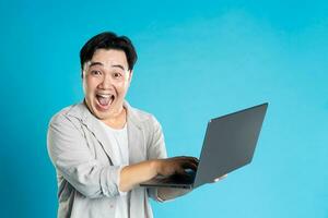 Immagine di asiatico uomo utilizzando il computer portatile su blu sfondo foto