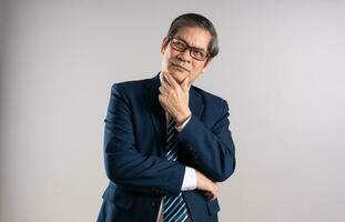 ritratto di un anziano asiatico uomo d'affari, in posa su un' blu sfondo foto