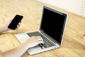 avvicinamento di attività commerciale femmina Lavorando con smartphone e il computer portatile nel caffè negozio piace il sfondo. foto