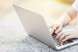 avvicinamento di attività commerciale femmina Lavorando con il computer portatile nel a il parco su ufficio all'aperto. foto