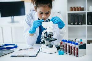 giovane scienziati conduzione ricerca indagini nel un' medico laboratorio, un' ricercatore nel il primo piano è utilizzando un' microscopio nel laboratorio per medicinale. foto