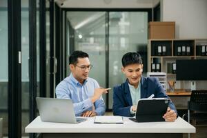 Due asiatico uomo d'affari discutere investimento progetto Lavorando e pianificazione strategia con tavoletta il computer portatile computer nel moderno ufficio. foto