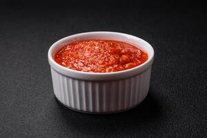 delizioso caldo speziato rosso salsa con sale e spezie nel un' ceramica ciotola foto