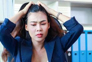 donna d'affari asiatica seduta in ufficio con lo stress le donne non sono felici al lavoro foto