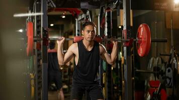 bodybuilding concetto. ritratto di muscolare giovane asiatico uomo formazione con manubri a palestra. fiducioso asiatico bodybuilder Lavorando su con leggero pesi nel fitness foto