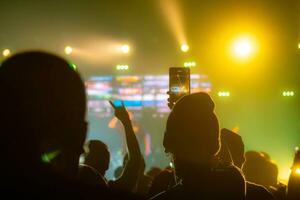 persone Tenere inteligente Telefono e registrazione e Fotografare nel concerto , silhouette di mani con mobile , evento sfondo concetto foto