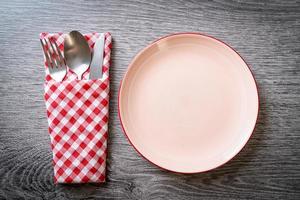 piatto vuoto o piatto con coltello, forchetta e cucchiaio su sfondo di piastrelle di legno foto