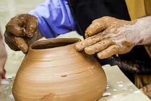 mani dell'uomo che lavorano e modellano l'argilla, vasaio in ceramica foto