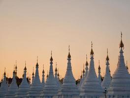 stupa bianco nel tempio di sanda muni, mandalay, myanmar al tramonto foto