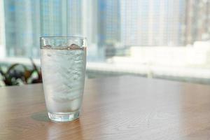 bicchiere d'acqua con ghiaccio sul tavolo foto