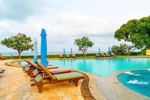 piscina con sedia o piscina per lettino e ombrellone intorno alla piscina con sfondo di spiaggia del mare a pattaya in thailandia foto