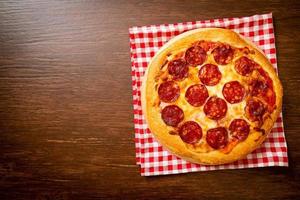 pizza ai peperoni su vassoio di legno - stile alimentare italiano foto