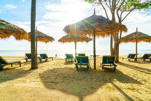 ombrelloni e sedie da spiaggia con palme da cocco e sfondo della spiaggia del mare e cielo blu - concetto di vacanza e vacanza foto