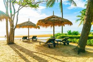 ombrelloni e sedie da spiaggia con palme da cocco e sfondo della spiaggia del mare e cielo blu - concetto di vacanza e vacanza