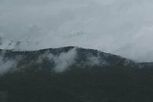 bellissimo panoramico Visualizza di nebbia e nuvole nel lontano strati montagne gamma con blu cielo nel mattina foto