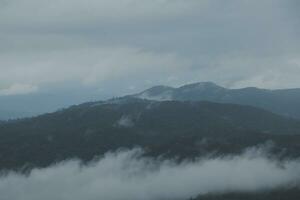 montagna gamma con visibile sagome attraverso il mattina blu nebbia. foto