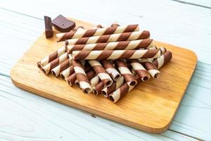 Rotolo di bastoncini di wafer al cioccolato su fondo di legno foto