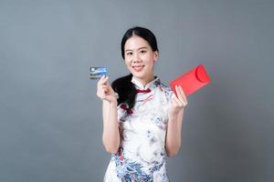la donna asiatica indossa un abito tradizionale cinese con una busta rossa o un pacchetto rosso e una carta di credito foto