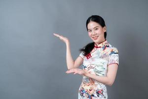 la bella giovane donna asiatica indossa il vestito tradizionale cinese con la presentazione della mano sul lato foto