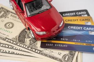 auto rossa su carta di credito e banconote in dollari americani, prestito auto, assicurazioni e concetti di tempo di leasing. foto