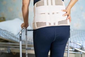 paziente della signora asiatica che indossa cintura di supporto per il dolore alla schiena per lombare ortopedico con deambulatore. foto